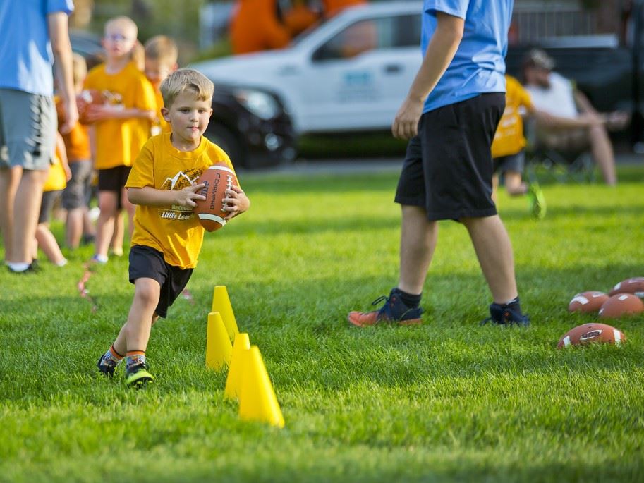 Photo of a young boy holding a football doing cone drills