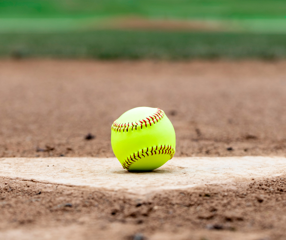 A softball resting on a home plate