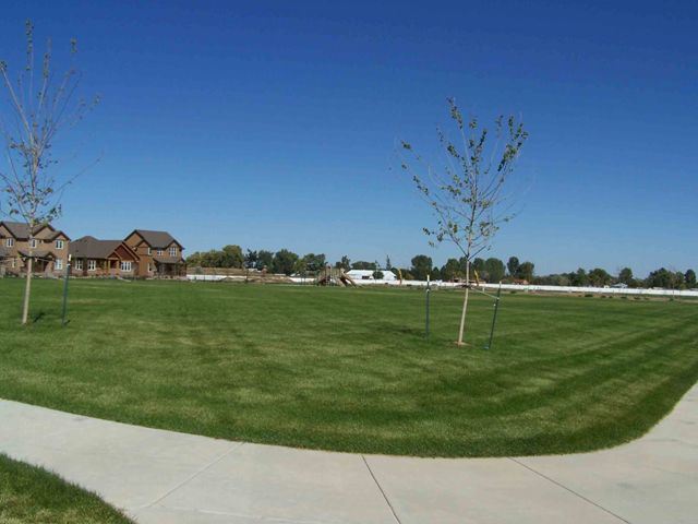 Paved Path Next Open Space with Playground and Houses in Background 1